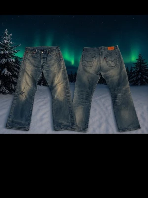Vintage Levis jeans (snygga fades) - Säljer ett Levis jeans 501 med raka ben och slitningar på låret och knät. Jeansen har klassisk femficksmodell, knappgylf och är tillverkade i denim. Perfekta för en avslappnad och trendig look. Midjan är 42cm och från topp till tå 102cm. Jenssen är i bra skick och priset är ej hugget i sten