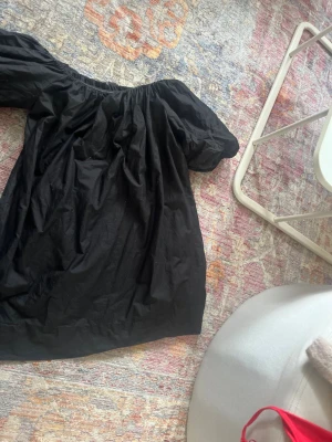 Svart offshoulder klänning Gina Tricot - Säljer en svart kortklänning från Gina Tricot i bomull. Klänningen har offshoulder-modell med puffiga ärmar och en lös passform. Perfekt för dig som gillar en enkel men trendig stil.
