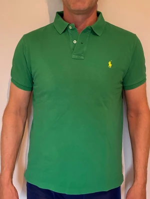 Grön pikétröja från Ralph Lauren, slim fit strl L - Grymt snygg grön pikétröja från Ralph Lauren med gul broderad logga på bröstet. Modellen är slim fit och storlek L. 