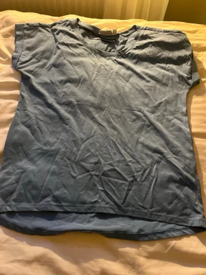 Ljusblå basic t-shirt - En enkel ljusblå t-shirt i mjuk bomull med rund hals och korta ärmar. Perfekt till jeans eller shorts för en avslappnad look. T-shirten har en rak passform och är lätt att matcha med andra plagg. Ärmarna är lite kortare än en vanlig t-shirt så lite mot linne hållet men en jätte fin tröja som även passar nu i början av hösten när det är lite varmare. 