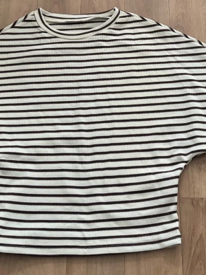 Randig croppad topp från SHEIN - Säljer en croppad topp från SHEIN med bruna och vita horisontella ränder. Toppen har rund halsringning och är gjord i ett mjukt ribbat material. Perfekt för dig som gillar en avslappnad men trendig stil.