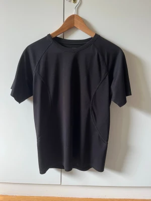 Svart tränings t-shirt från TTL strl M - En enkel och stilren svart tränings t-shirt med korta ärmar och rund hals. Har defekter på baksidan av tröjan, se bild. Storlek M.