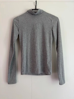 Grå polotopp - Säljer en enkel grå polotopp med lång ärm från Gina Tricot. Använd nån enstaka gång så i fint skick. Storlek xs 