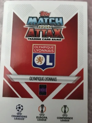 Match Attax Olympique Lyonnais kort - Säljer två Match Attax samlarkort från Topps med Olympique Lyonnais-tema. Ett kort visar klubbens logga och det andra spelaren Rayan Cherki i vit matchdräkt. Perfekt för dig som gillar fotboll och samlarkort.
