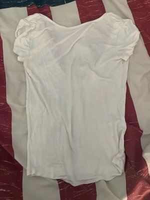 Vit basic t-shirt med v-ringning - En enkel vit t-shirt med djup v-ringning och korta ärmar. T-shirten har en mjuk och följsam passform, perfekt till jeans eller kjol. Tillverkad i ett tunt och bekvämt bomullsmaterial.