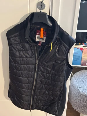 Svart dunväst från Parajumpers - (PRISET ÄR DISKUTERBART) Snygg svart dunväst från Parajumpers med quiltad design och dragkedja framtill. Västen har en gul detalj vid kragen och flera praktiska fickor med dragkedja. Perfekt för lager-på-lager och streetwear-vibe.