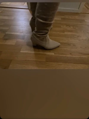 Beige stövletter med klack - Snygga beige stövletter med spetsig tå och bred klack. Tillverkade i ett mockaliknande material som ger en mjuk och trendig look. Perfekta för dig som vill ha en stilren och modern sko till hösten eller vintern.