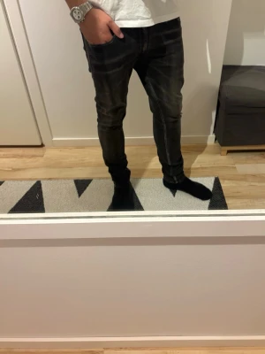Replay Jondrill - Säljer ett par svarta slim fit jeans med klassisk femficksdesign och normal midja. Jeansen har diskreta slitningar och smal passform som sitter snyggt längs benen. Perfekta för dig som gillar en stilren och modern look.