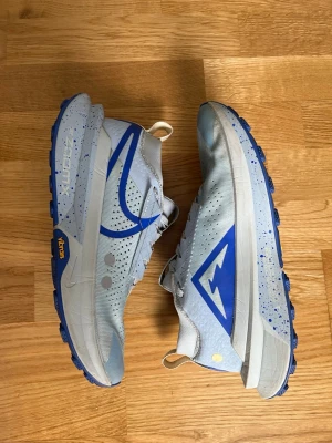 Ljusblå Nike sneakers med mesh - Snygga ljusblå sneakers från Nike med ventilerande meshmaterial och grå detaljer. Skorna har en blå swoosh på sidan, vita och grå skosnören samt vit sula med blå inslag. Perfekta för dig som gillar sportig och modern stil.
