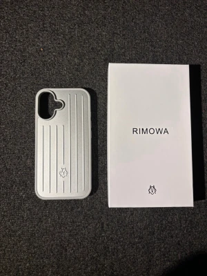 mobilskal från Rimowa till iPhone 16 - Snyggt och stilrent mobilskal från Rimowa i silverfärgad hårdplast med klassiska räfflade linjer. Skalet har en modern design och passar perfekt för dig som vill ha ett exklusivt och tåligt skydd till din mobil.