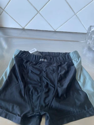 Svarta och grå boxerkalsonger i polyamid +lyckra - Snygga boxerkalsonger i svart med grå sidor. De har en bekväm resår i midjan och är tillverkade i ett mjukt och stretchigt material som sitter skönt hela dagen. Perfekta för dig som gillar en sportig och stilren look.