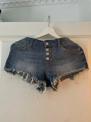 Blå jeansshorts med fransig kant - Säljer ett par blå jeansshorts med fransig kant. Midrise midja.