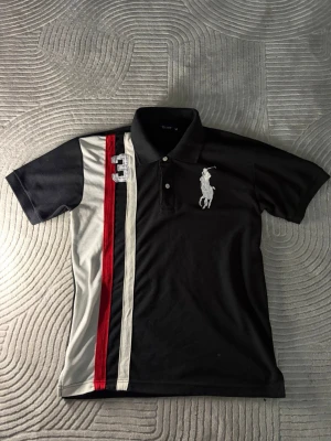 Ralph lauren piké - Svart pikétröja med vita och röda ränder. Tröjan har en stor broderad logga på bröstet och även en trea på andra sidan. Tröjan är i storlek M och passar perfekt på ungefär 170-180 beroende på hur du vill att den ska sitta. Fräsch tröja utan synliga defekter. I kragen står det även Ralph lauren. Har även fler liknande ralphlauren pikéer i andra storlekar och färger på min profil så gå in och kika vetja! Och såklart om man köper fler blir priset billigare 😉Skriv vid funderingar 👍