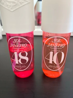 Sol de Janeiro Cheirosa 48 & 40 mist - Två Sol de Janeiro Cheirosa Fragrance Mist, nummer 48 och 40. Flaska 48 är rosa och flaska 40 är orange, båda med vita lock och tydlig märkning på framsidan. Perfekta för dig som älskar fräscha och söta dofter. Mängden som finns kvar syns på flaskorna 