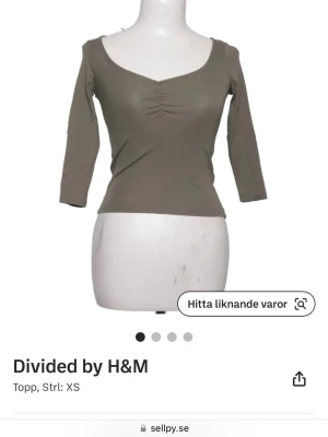 Olivgrön topp med trekvartsärm H&M - Snygg olivgrön topp från H&M Divided med trekvartsärm och rynkdetalj vid bysten. Toppen har en djup rundringning och är figurnära i modellen, perfekt för en trendig och enkel look.