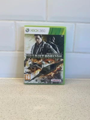 Ace Combat Assault Horizon Xbox 360 - Säljer spelet Ace Combat Assault Horizon till Xbox 360. Omslaget är grönt och spelet är från Namco. Actionfyllt flygstridsspel med realistiska flygplan och explosiva miljöer. Perfekt för dig som gillar militär action och flygsimulatorer. Fungerar toppen!