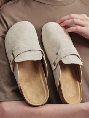 Clogs  - Snygga beige tofflor i mockaimitation med justerbart metallspänne på sidan. De har öppen häl, mjuk innersula och svart sula undertill. Perfekta för chill dagar hemma eller när du vill ha något bekvämt på fötterna. De är i storlek 42 men är lite för smala där bak! Har aldrig använts!