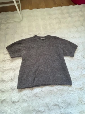 Grå brun stickad t-shirt  - En enkel och stilren grå brun stickad t-shirt med korta ärmar och rund hals. 