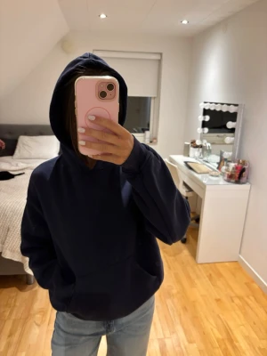 Mörkblå oversized hoodie - Mörkblå hoodie med luva och stor känguruficka framtill. Modellen är oversized och har ribbade muddar vid ärmslut och nederkant. Perfekt för en avslappnad och chill stil. Passar till jeans eller mjukisbyxor.
