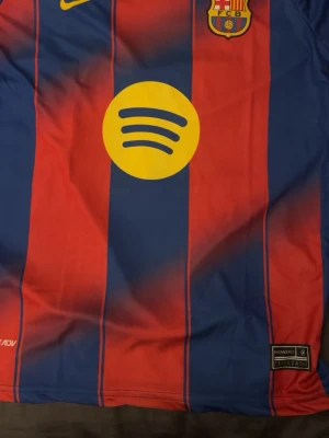FC Barcelona matchtröja blå/röd - Säljer en FC Barcelona matchtröja från Nike med klassiska blå och röda vertikala ränder. Tröjan har klubbmärke på bröstet, Nike-logga och stor gul Spotify-logga i mitten. Tillverkad i lätt och ventilerande Dri-FIT-material.
