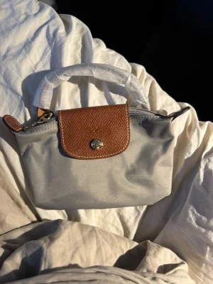 Longchamp mini bag - Säljer en helt ny longchamp mini väska. Nypris 1299kr, mitt pris 499kr. OBS sista bilen på den mörk blåa väskan är endast för att visa upp axelremsbandet. Väskan är alltså ljus grå💕