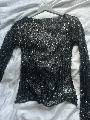Svart glittrig långärmad topp - Säljer denna svarta långärmad topp täckt med glittriga paljetter, från Gina tricot. Använd fåtal gånger och är i bra skick🥰