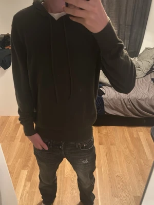 Grön kashmir hoodie - Säljer en enkel och stilren mörkgrön hoodie med huva och dragsnören. Hoodien har en avslappnad passform och långa ärmar. Perfekt för dig som gillar en clean och bekväm look.