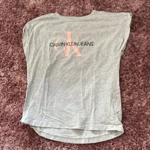 En grå T-shirt från Calvin klein med rosa text, sparsamt använd, pris kan förhandlas! Storlek är 16 år men passar både S och M.