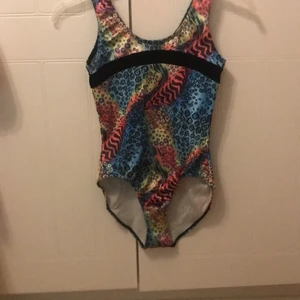 Gymnastikdräkt färgglad  - Färgglad Gymnastikdräkt i skönt material och glittrig. Köpte den pga hur fin den är men den var redan för liten då, använd ca 2 gånger eftersom den är för liten! Hör av er om ni har frågor eller fler bilder. Köpt för ca 400kr men säljs för 240+frakt