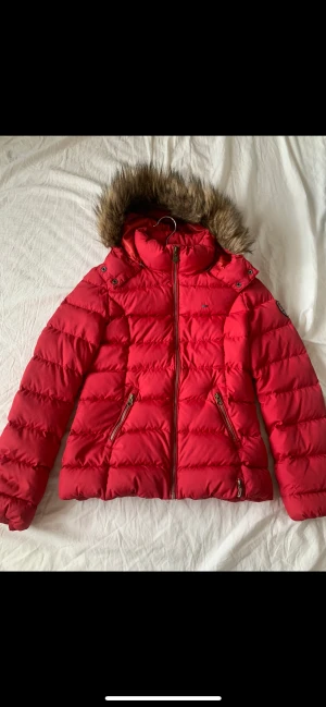 Vinterjacka  - Röd vinterjacka från Tommy hilfiger i storlek S. Pälsen är fake och jackan i sig är i bra skick. 
