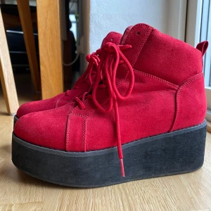 Röda platåskor  - Fina röda platåskor från skopunkten. Inte mycket använda så i fint skick. De har snörning och en dragkedja på insidan. Platån är 6 cm vid hälen och planat ut till ca 3,5 vid tån.  Köparen står för frakt💕