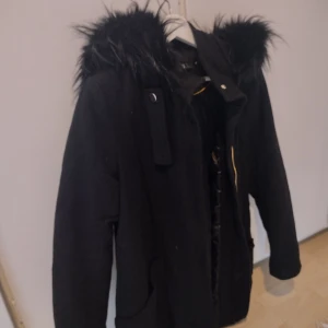 Ullkappa med päls  - En fin ullkappa/jacka med stor päls på luvan samt gulddetaljer. 