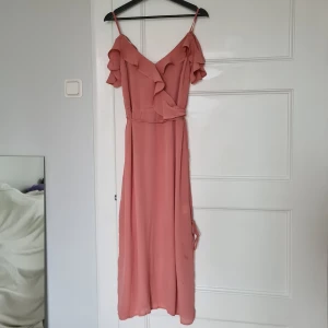 Lindex maxiklänning med volanger & slits - Lindex maxiklänning, offshoulder med volanger & slits på båda sidor. HELT NY, prislappen kvar. Knapp mellan brösten. Band som kan knyta smickrande för att framhäva midjan.  (Har tyvärr ingen bild med klänningen på)