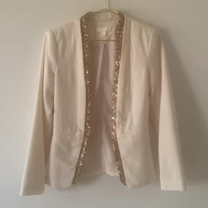 Benvit kavaj  - Figursydd kavaj med guld glittrig detaljer från H&M i strl 34. Köpt i London för många år sedan, använd ett fåtal gånger. 