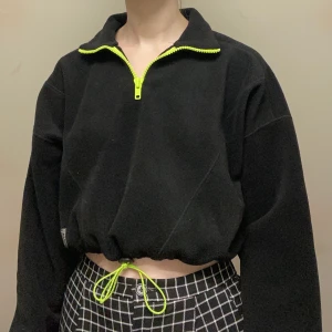 Urban Outfitters polotröja S - Svart polotröja från Urban Outfitters i fleece med neongröna detaljer. Sparsamt använd! Pris går att diskutera, köparen står för frakt :)