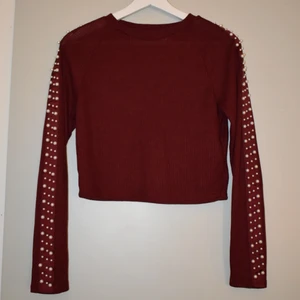 Röd tröja med pärlor  - Ribbad tröja med pärlor på ärmarna. Storlek S. Endast använd fåtal gånger. 