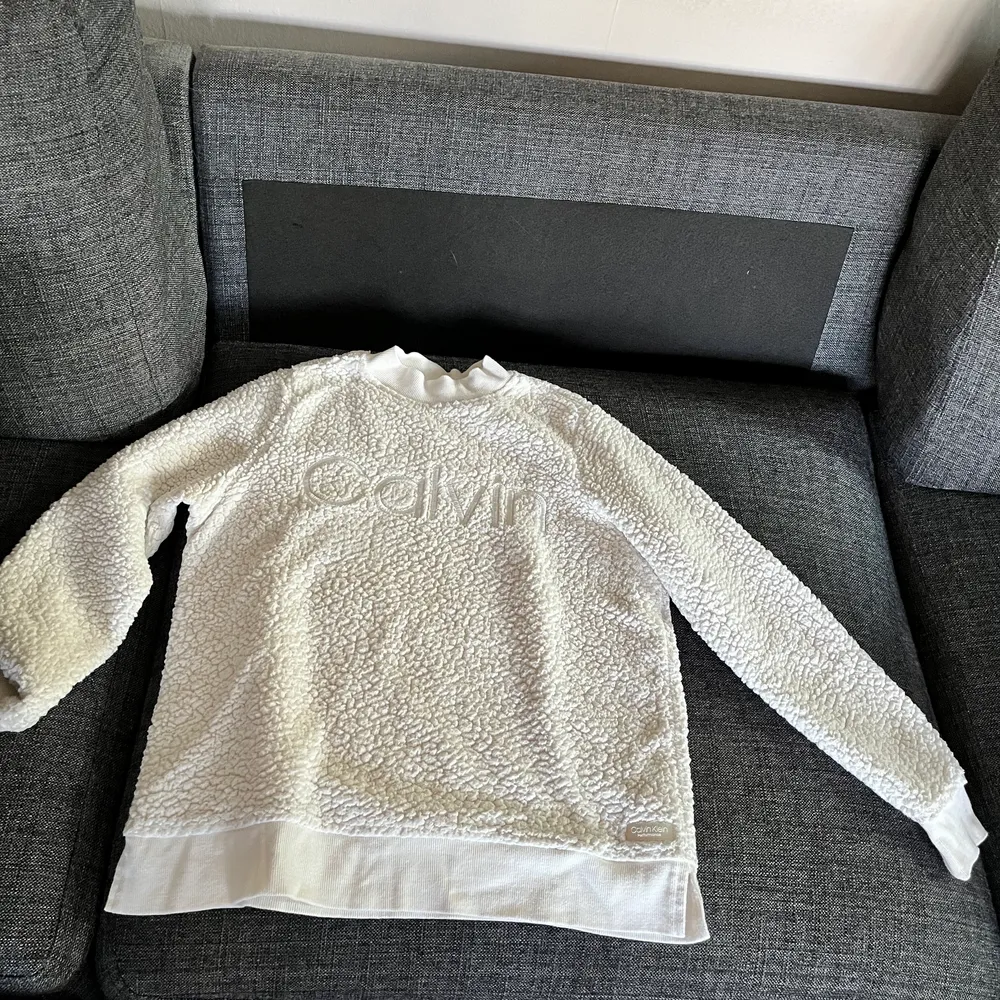 Det är en vit fluffig tjocktröja från Calvin Klein. En mycket fin tröja. Den är inköpt från en Calvin Klein butik i USA 2019. Köparen står för frakten, priset kan diskuteras. Hör av er vid fler bilder eller frågor om plagget.😊. Tröjor & Koftor.