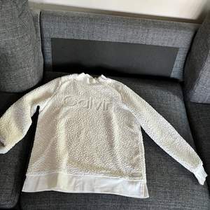 Det är en vit fluffig tjocktröja från Calvin Klein. En mycket fin tröja. Den är inköpt från en Calvin Klein butik i USA 2019. Köparen står för frakten, priset kan diskuteras. Hör av er vid fler bilder eller frågor om plagget.😊