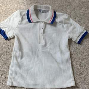 En vit tröja med lite blått och rosa säljer för den inte kommit till användning 