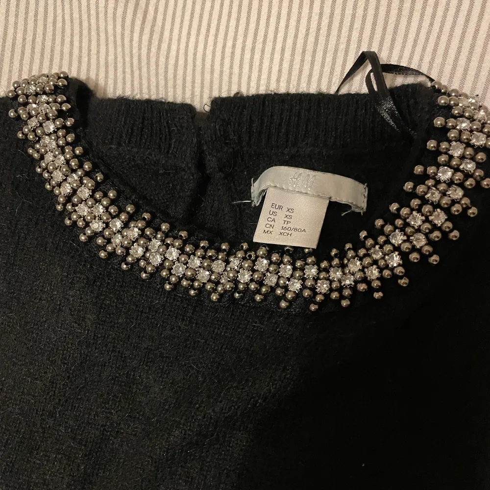 Svart stickad tröja från hm i storlek xs med pärlor och diamanter/stenar fastsydda på kragen, lite tecken på användning syns men annars bra skick❤️‍🔥❤️‍🔥. Stickat.