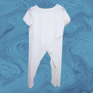 T-shirt - asymmetrisk - Flowy, vit t-shirt med asymmetrisk design. Gjord av tunt see-through material med dubbla lager på fram-baksida = ej see-through vid rygg/byst/mage. Aldrig använd - Nyskick. 
