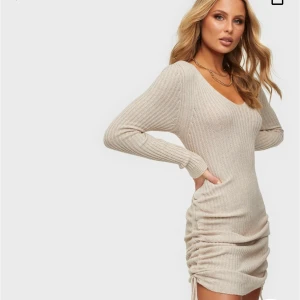 Stickad långärmad klänning - Säljer denna fina beiga stickade klänningen från Nelly. Jättefin och mjukt material. Aldrig använd och med prislappen kvar. Köparen står för frakten💗