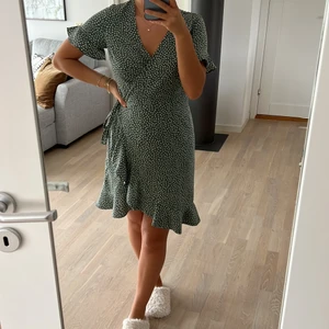 Grön omlottklänning - Grön prickig klänning som man knyter omlott ifrån Vero Moda. Superform till sommaren och perfekt med en stickad tröja över. Endast använd 1 gång.