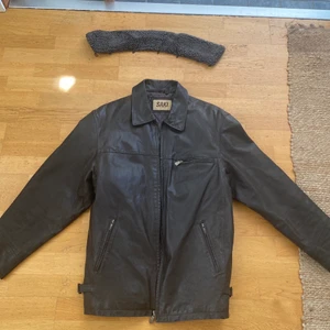 Vintage saki läderjacka  - Mörkbrun vintage saki läderjacka. Storlek 58 i herrmodell, men fungerar på de flesta ifall man vill att den ska vara oversize. Något stor på mig därav jag säljer. Super fint skick då det är en lädervara och blir därför bara bättre med åren. Finns nackkrage med ludd som går att ta av och på. Original pris upp mot 3000.