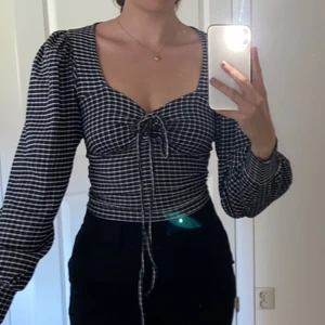 Topp - En rutig, svart vit topp med snörning vid brösten. Haft på mig den enstaka ggr. Den är storlek XS men passar mig som är S