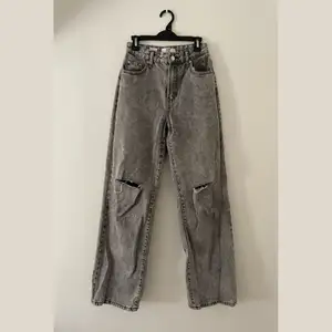 Högmidjade raka jeans från Bershka i grå med hål på knäna. Storlek 34 men passar även mig som är 36. Skriv för bilder med jeansen på, för bättre bild av passform osv. Nypris 499kr, säljer för 200kr + frakt (frakten kan variera utöver skrivet pris).