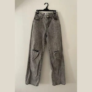 Bershka jeans - Högmidjade raka jeans från Bershka i grå med hål på knäna. Storlek 34 men passar även mig som är 36. Skriv för bilder med jeansen på, för bättre bild av passform osv. Nypris 499kr, säljer för 200kr + frakt (frakten kan variera utöver skrivet pris).