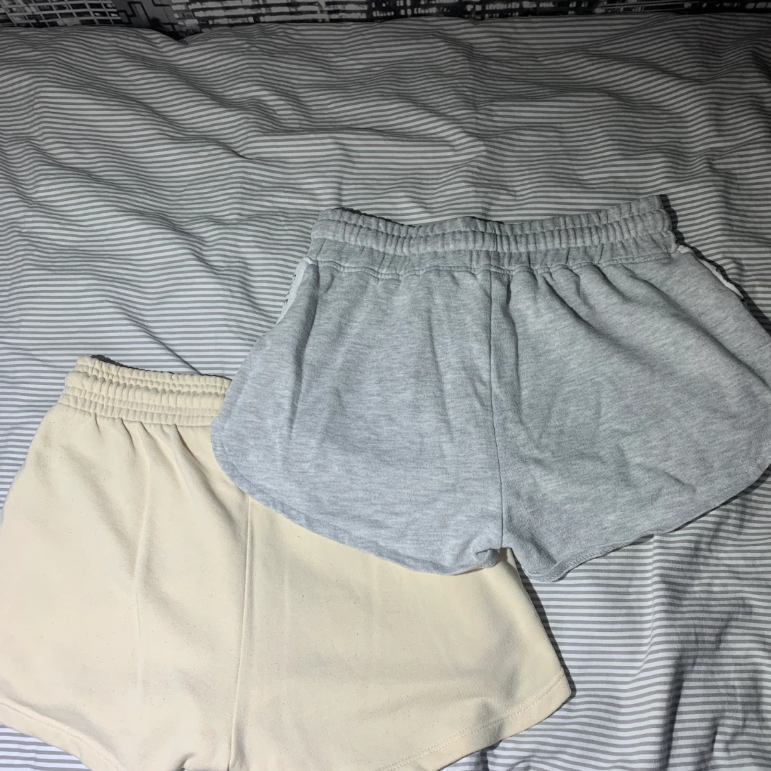 Grå shorts med text på sidorna där det står ”one of a kind” och beiga shorts utan tryck. - 90