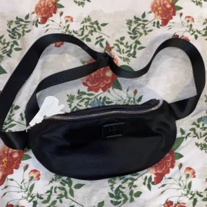 svart midjeväska väska från Carin wester  - En aldrig använd midjeväska från märket Carin Wester på Åhléns. Väldigt bra skicka och med justerbart band.