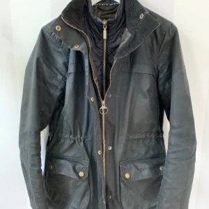 Barbour jacka storlek 36 - En vinter/höstjacka från Barbour storlek 36. Modellen heter Barbour Dartford wax färgen heter Navy och är svartblå. Avtagbar luva med avtagbar fuskpäls. Ställbar midja. Manchesterkrage. Djur och rökfritt hem. Nypriset var 4000kr.